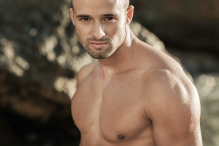 Portrait of a handsome young muscular man in swimtrunks with water ocean backgroundの写真素材
