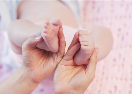 Baby feet cupped into mothers hands の写真素材