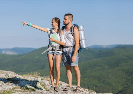 Two young tourists with backpacks relaxing on rocksの写真素材