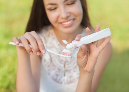 Young woman holding a toothbrush and placing toothpaste on it の写真素材