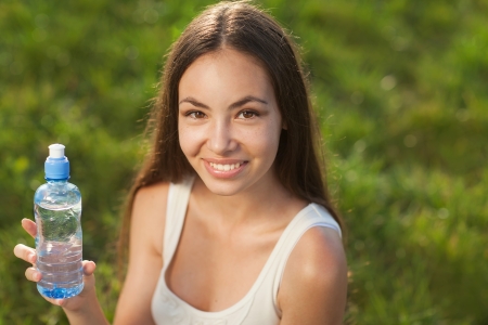 Portrait half face of young woman holding water bottle at summer green parkの写真素材