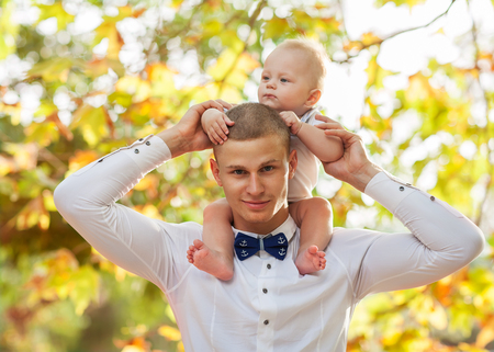 Happy young man holding a smiling 7-9 months old babyの写真素材