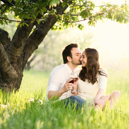 loving man and woman in the park laughing and drinking wineの写真素材
