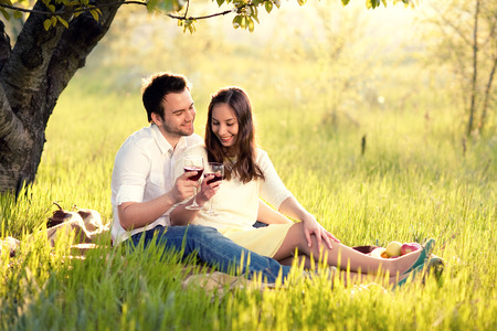 loving man and woman in the park laughing and drinking wineの写真素材