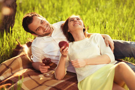 happy couple in love at a picnic eating apples and drinking wineの写真素材