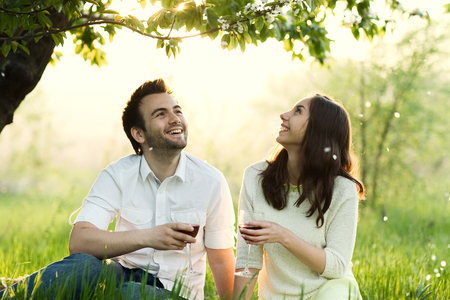 loving man and woman in the park laughing and drinking wineの写真素材