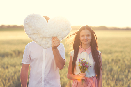 Portrait of couple in love that holdings heart - cloud in the field on sunset  Close man faceの写真素材