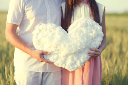 Young couple kissing behind white heart cutout in the natureの写真素材
