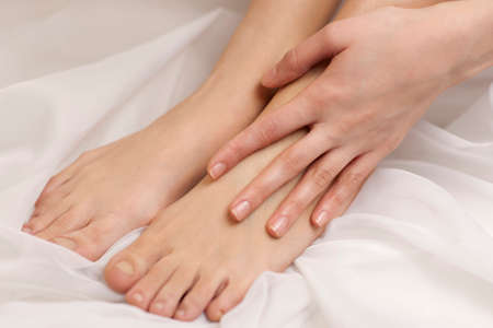 Lower section of young woman applying body lotion to her legの写真素材