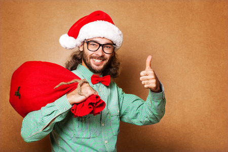 Hipster Santa Claus with the bag of the presents shows classの写真素材