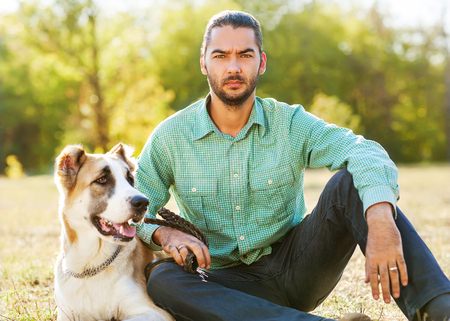 Man and central Asian shepherd walk in the park. He keeps the dog on the leash.の写真素材