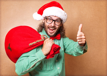 Santa Claus with a bag of gifts looking at camera and showing sign of coolの写真素材