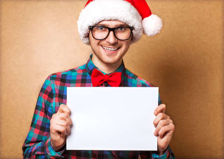 Hipster guy in the hat of Santa Claus holding a sheet of paper. Space Mineの写真素材