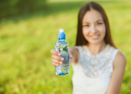 Portrait half face of young woman holding water bottle at summer green parkの写真素材