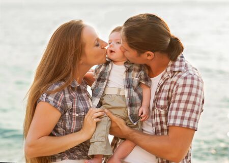 Happy mother, father and daughter in sunset