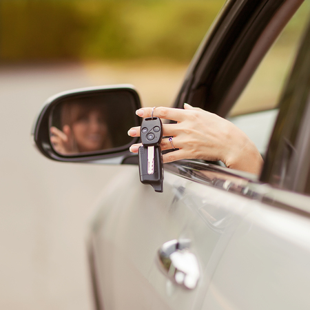 Cheerful girl holding car keys from windowの写真素材