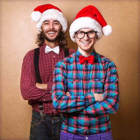 Two emotional Santa Claus dressed in clothes hipster standing near a wallの写真素材