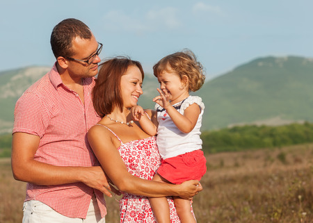 Happy mother, father and daughter in  the mountains at sunsetの写真素材