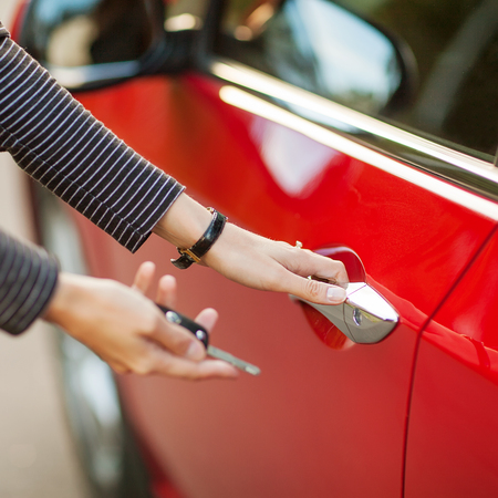 Beautiful young girl with car key in hand and opens the carの写真素材