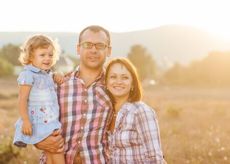 Happy mother, father and daughter in  the mountains at sunsetの写真素材