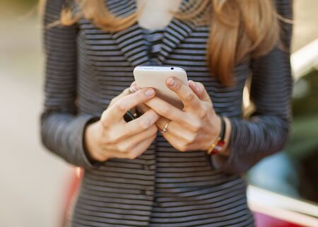 Young beautiful woman writes an SMS to your mobile phone.の写真素材
