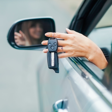 Cheerful girl holding car keys from windowの写真素材