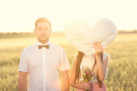 Portrait of couple in love that holdings heart - cloud in the field on sunset. Close man faceの写真素材