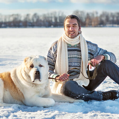 Man and central Asian shepherd playing with his dog outdoors