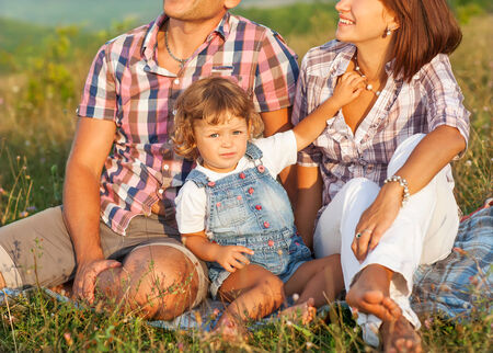 Happy mother, father and daughter in sunsetの写真素材