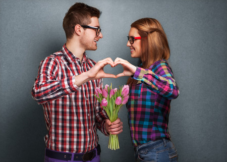 Young couple in love make a heart and hands are holding a bouquet of tulips  The concept of Valentineの写真素材