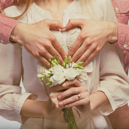 Young couple in love make a heart and hands are holding a bouquet of tulips. The concept of Valentine's Dayの写真素材