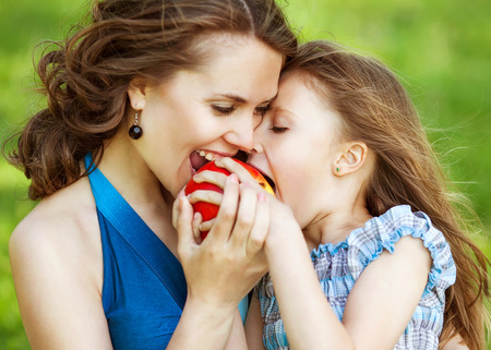 Mother and her child enjoy the early spring, eating apple, happy.の写真素材