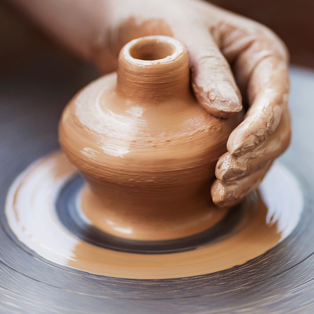 Potter hands making in clay on pottery wheel. Potter makes on the pottery wheel clay pot.の写真素材