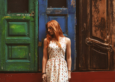 red-haired girl on the street outside wooden doors