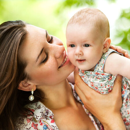 Portrait of happy loving mother and her baby outdoorsの写真素材
