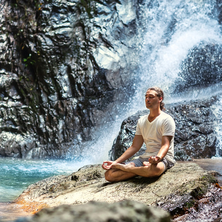 young man yogi  engaged in the waterfall in the mountains yogaの写真素材