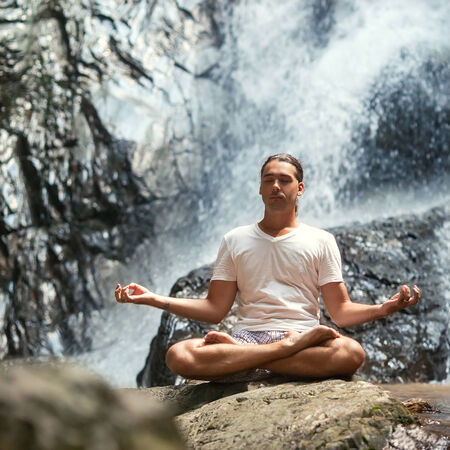 young man yoga engaged in the waterfall in the mountains yogaの写真素材