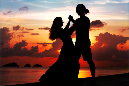 man and woman dancing smiling at sunsetの写真素材