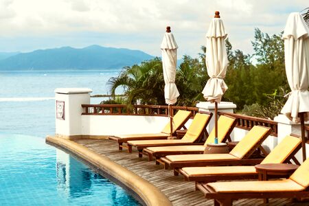 swimming pool with beds overlooking the sea and mountainsの写真素材