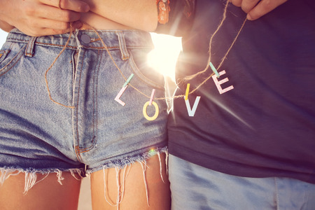 Young couple in love walking in the park holding hands looking in the sunset, words loveの写真素材