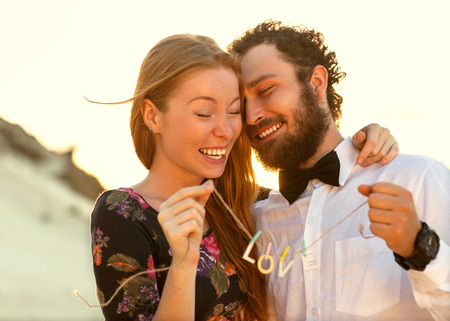 Young couple in love walking in the park holding hands looking in the sunset, words loveの写真素材