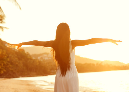 Beautiful girl walking on the beach at sunset, freedom conceptの写真素材