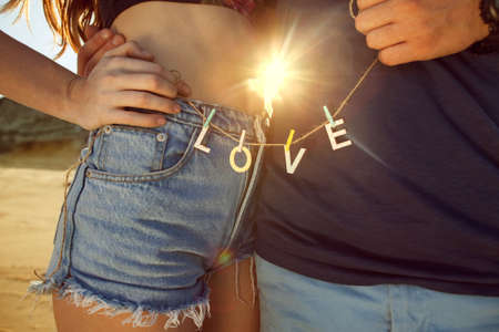 Young couple in love walking in the park holding hands looking in the sunset, words love, concept of Valentine's Dayの写真素材