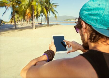 freelancer working guy sitting on the beach with views of palm trees