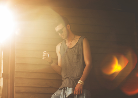 Portrait of young beautiful fashionable man against wooden wall. Hipster style guyの写真素材
