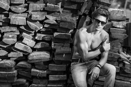 Stylish man in sunglasses sitting near a wooden background, fashion conceptの写真素材