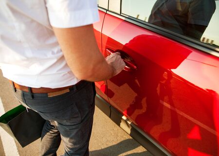 guy opens his car and holds the handle of the machine, with purchases from shop