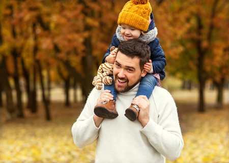 Dad and little daughter having fun in the park happy to play in autumn.の写真素材