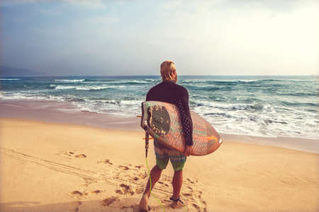 Surfer at the sea is standing with a surf board bright color.の写真素材