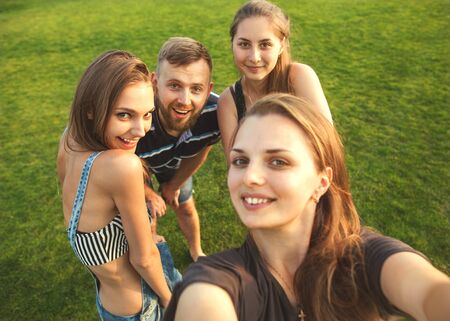 cheerful company of friends make selfie on nature, smiling happily
